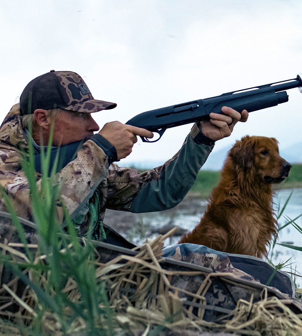Tyce Erickson shooting with his golden retriever beside him